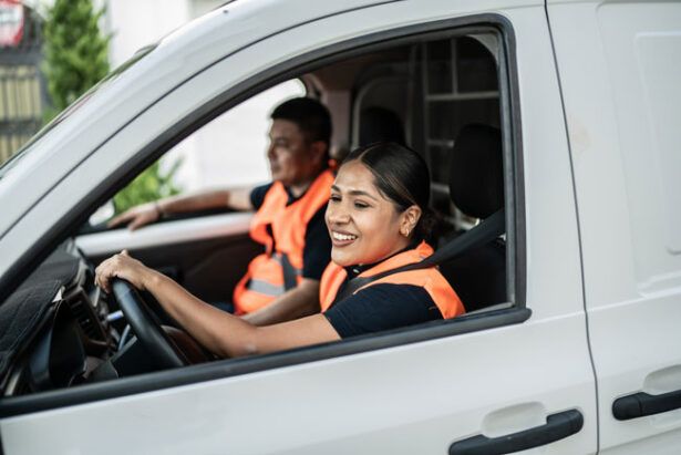 Two people from a commercial cleaning crew drive in their van from the business fleet.