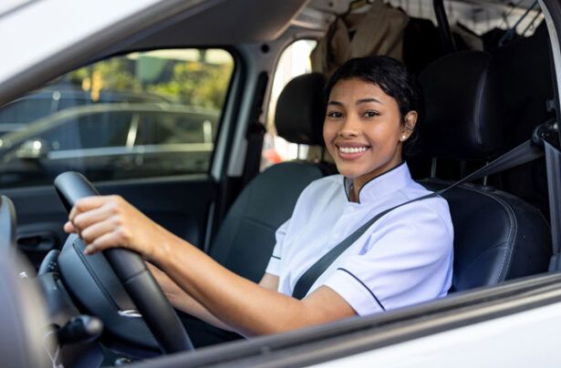 A fleet driver for a cleaning company smiles as she drives the company van.