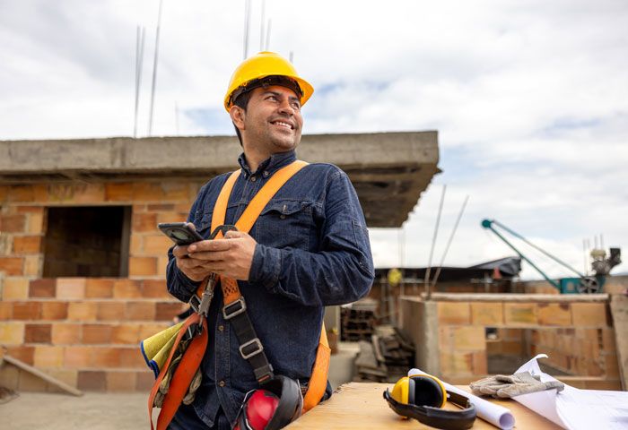 A building contractor on a jobsite reviews his fleet’s fuel usage via their fleet card from his cell phone.