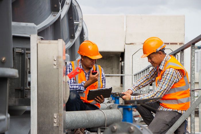 Workers check in with their fleet card app on laptops at their HVAC job.