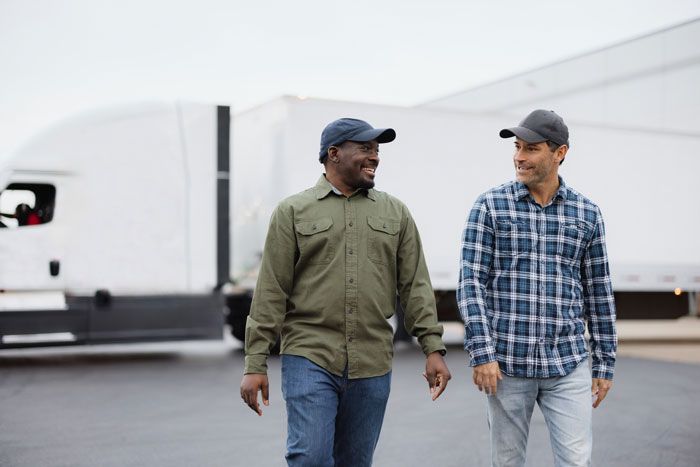 Two happy truck driver men walk away from their semi truck.