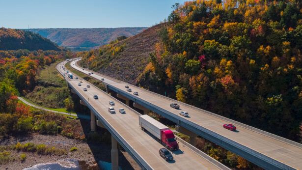 A bird’s eye view of a highway near mountains filled with vehicles.