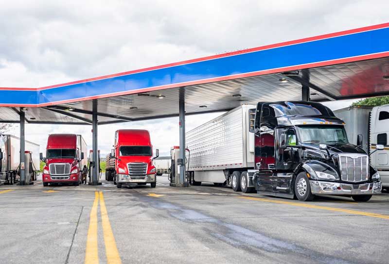 Semi trucks at fuel bays at a gas station.