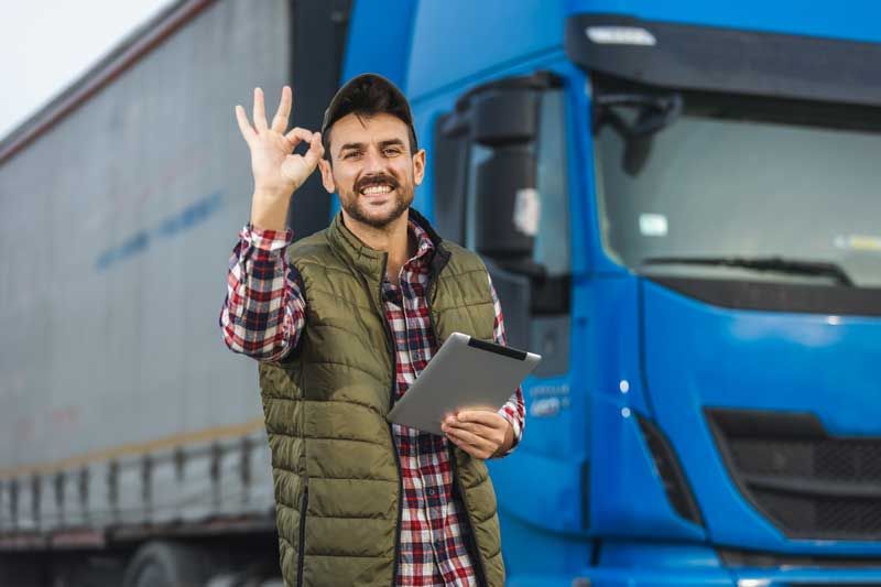 A happy fleet owner reviews maintenance checks on his tablet outside one of his fleet vehicles.